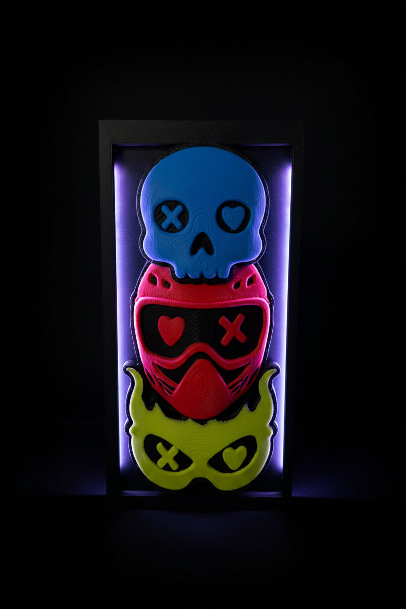 3D printed Lights Out shadow box display with blue skull, red helmet, and yellow demon mask on bookshelf