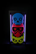 3D printed Lights Out shadow box display with blue skull, red helmet, and yellow demon mask on bookshelf
