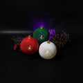 3D printed holiday LED ornaments in red, green, and white with gold ring topper on white background
