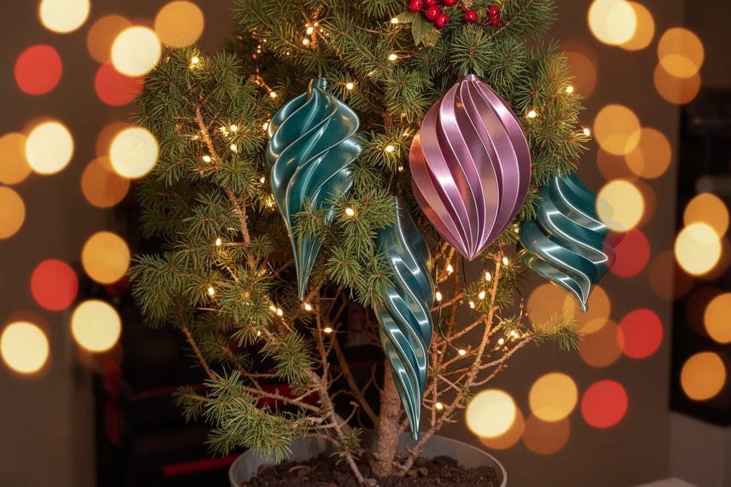 Teal and pink holiday vase mode spiral ornaments hanging on a small pine tree