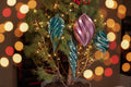 Teal and pink holiday vase mode spiral ornaments hanging on a small pine tree