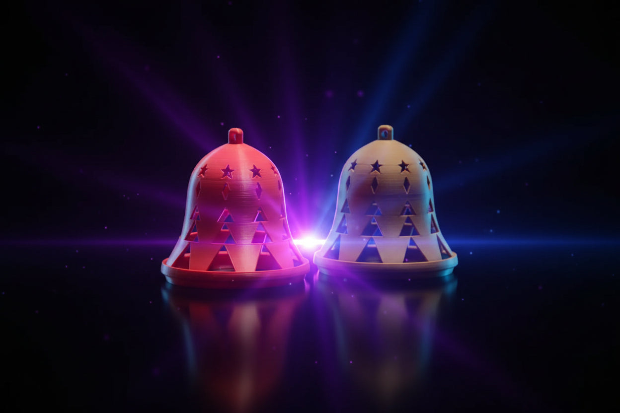 3D printed Christmas tree cutout holiday bell ornaments in red and tan on a wood surface