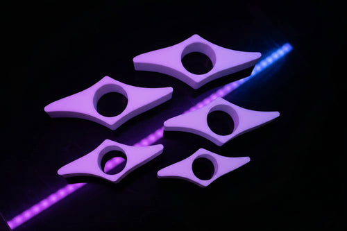 Set of four 3D printed star-point book page holders in matte white laid flat on wooden surface