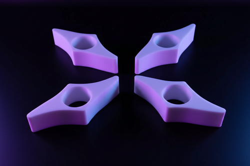 Four 3D printed book page holders standing upright on wooden surface showing depth and star-point design