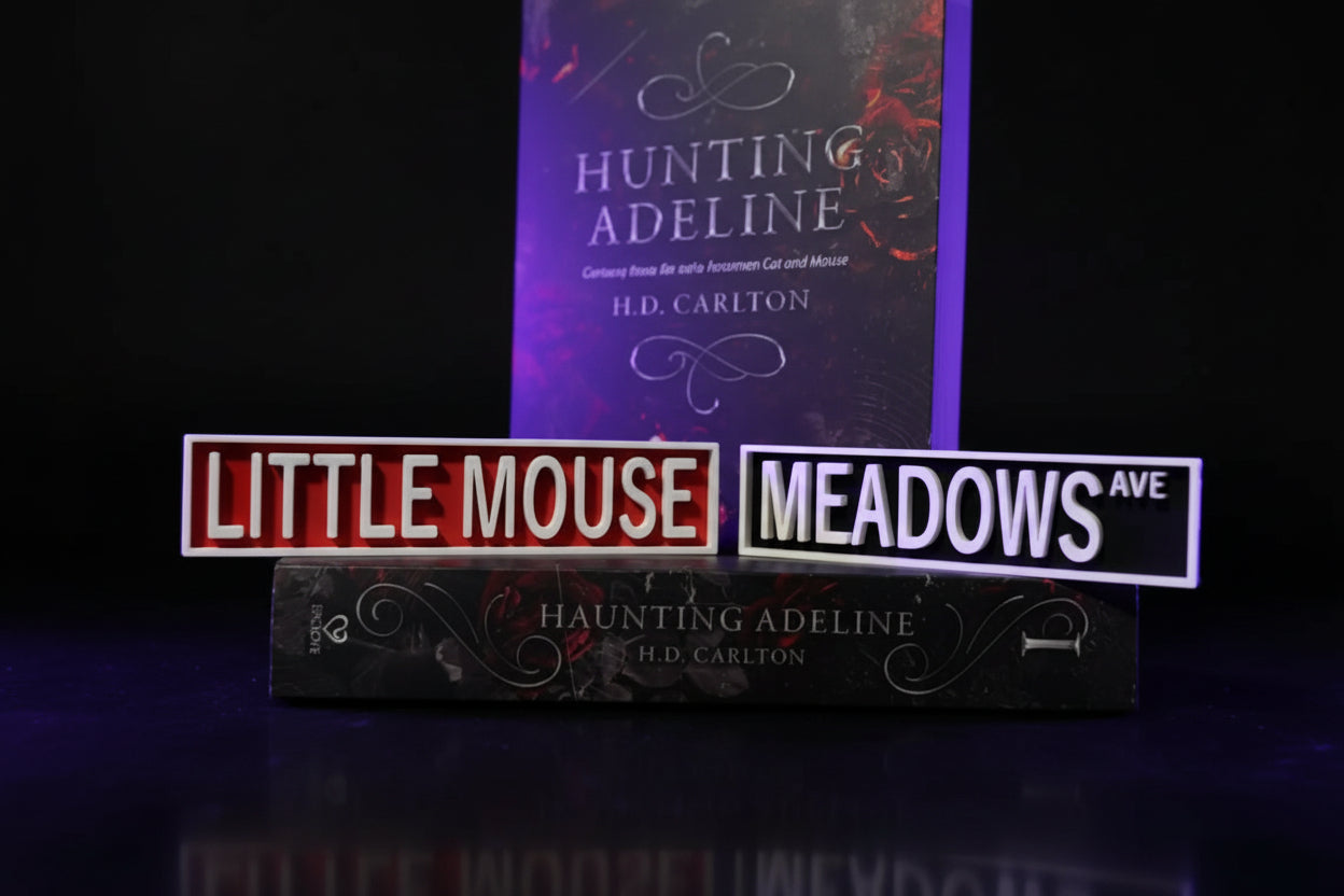 3D printed Little Mouse Meadows Ave street sign set displayed with Haunting Adeline and Hunting Adeline books by H.D. Carlton