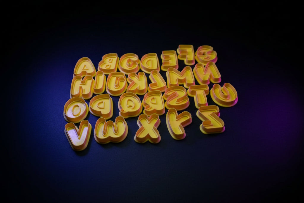 Bubble letter alphabet cookie cutters styled on a wooden table with baking props